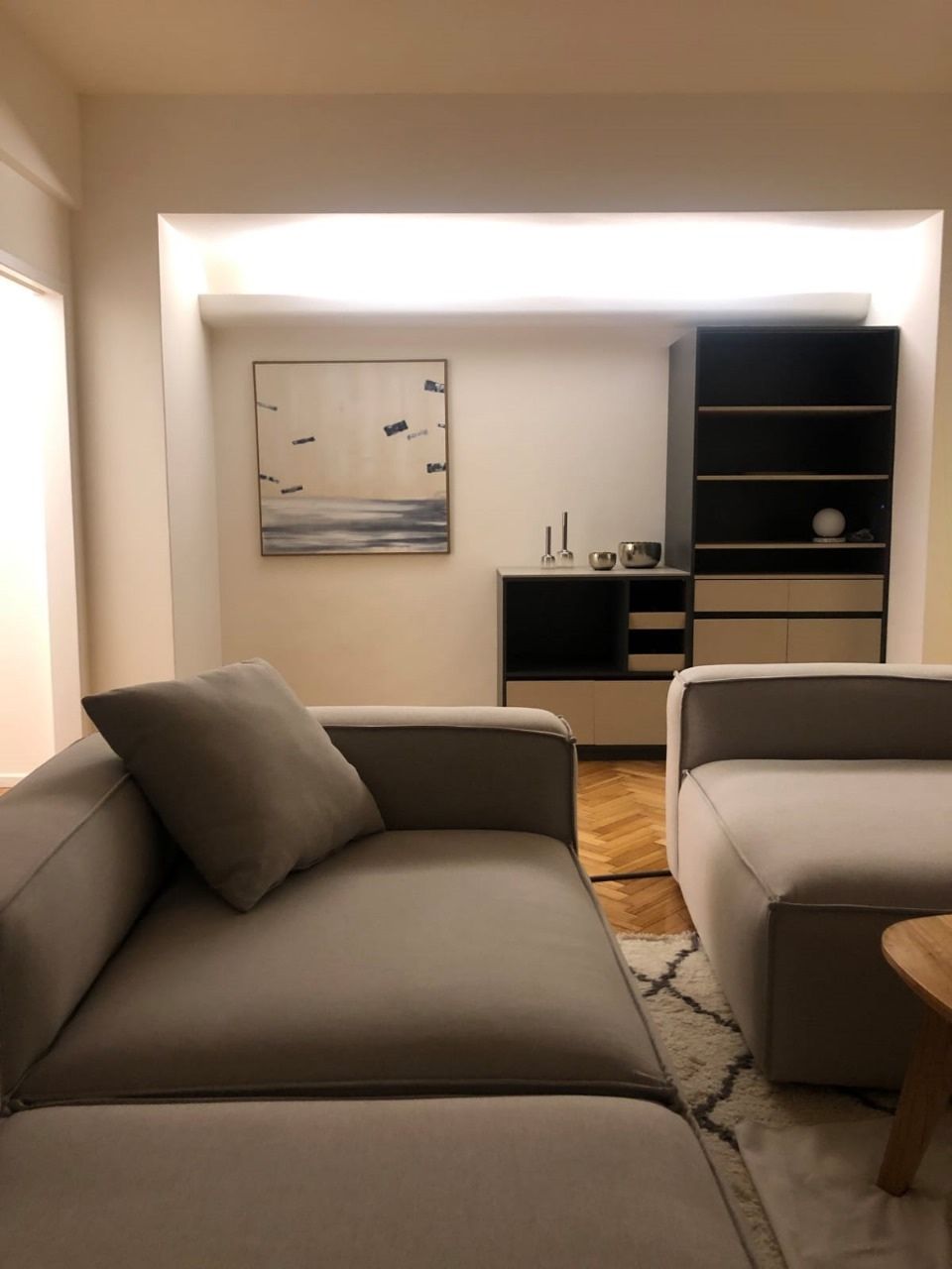 Living con mueble bar y biblioteca a medida, iluminación en cornisa y piso de parquet